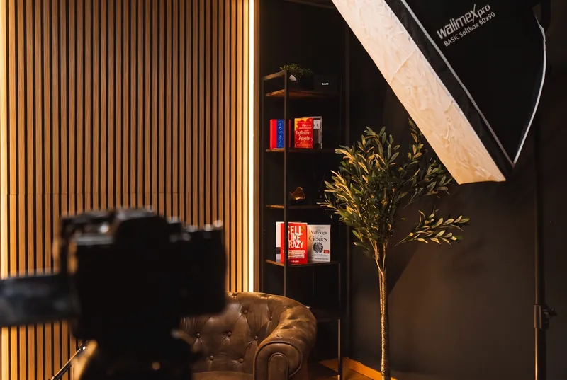 Detail: Softbox, Bücherregal und Olivenbaum neben der Holzlamellenwand, Kamera im Vordergrund