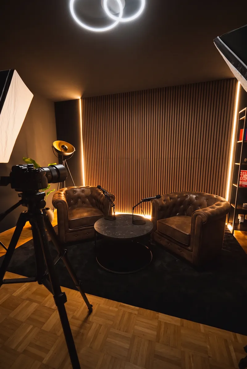 Das Set im Hochformat: Kamera auf dem Stativ, Softbox, Sessel und Tisch, Ringleuchte an der Decke